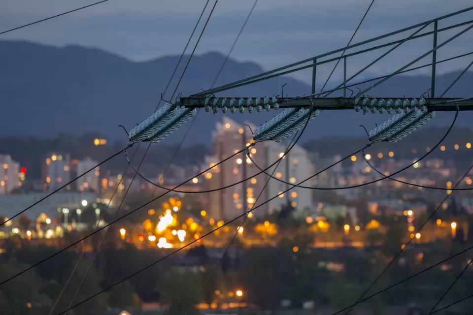 Close-up of power lines with urban night scene blurred in background.